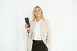 © Westend61 - Businesswoman looking up holding mobile phone while charging