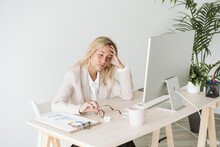 Tired Businesswoman Sitting At Desk In Office