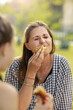 © Johnér - Smiling woman eating food outdoors