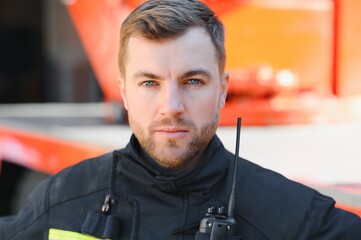 Fireman (firefighter) in action standing near a firetruck. Emergency safety. Protection, rescue from danger.