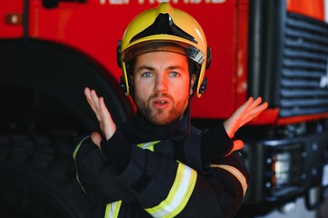 Firefighter portrait on duty. Photo fireman with gas mask and helmet near fire engine.