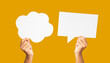 © meeboonstudio - Close-up of hands holding a white speech bubble against an orange background