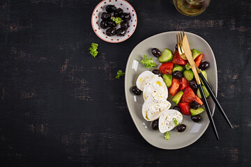 Wall Mural - Greek salad of fresh cucumber, tomato, burrata cheese and black olives with olive oil. Healthy food. Top view, flat lay