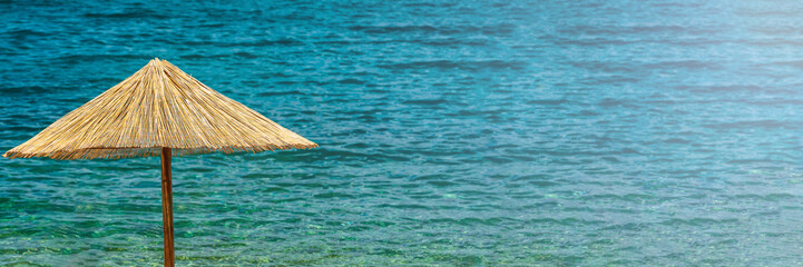 Wall Mural - Panorama of parasol made of straw in front of blue sea