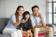 © aekkorn - Happy Asian family lifestyle enjoy watching TV in living room at home. Happy Asian family portrait with mother, father and daughter