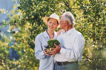 Smiling and holding vegetables. Daughter is with her senior father in the garden at daytime