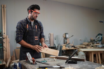 Contemporary Carpenter Working, Portrait of modern carpenter making wood furniture while working in joinery lit by sunlight with factory background on small business concept, copy space