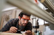 © FotoArtist - Contemporary Carpenter Working, Portrait of modern carpenter making wood furniture while working in joinery lit by sunlight with factory background on small business concept, copy space