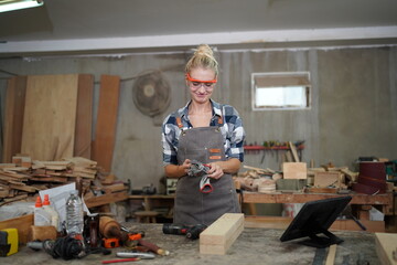 Contemporary Carpenter Working, Portrait of modern carpenter making wood furniture while working in joinery lit by sunlight with factory background on small business concept, copy space