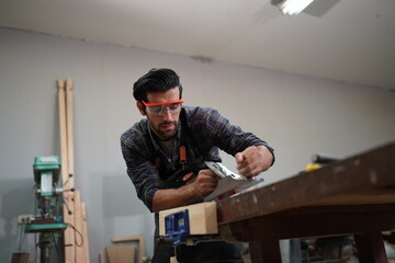 Contemporary Carpenter Working, Portrait of modern carpenter making wood furniture while working in joinery lit by sunlight with factory background on small business concept, copy space