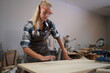 © FotoArtist - Contemporary Carpenter Working, Portrait of modern carpenter making wood furniture while working in joinery lit by sunlight with factory background on small business concept, copy space