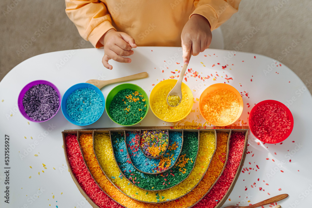 Color Rice Math Activity Child hands playing colored rice and make rainbow. Child filled the ...