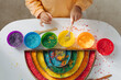 © igishevamaria - Child hands playing colored rice and make rainbow. Child filled the rainbow with bright rice. Montessori material. Sensory play and learning colors activity for kids.