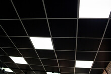 Black Ceiling With Neon Light Bulbs In Uprisen View. Fluorescent Light In Office Interior With Dark Ceiling.
