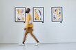 © AnnaStills - Blurred motion of African young man walking along art gallery with pictures on the wall