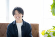 © rrice - リビングのソファーに座りリラックスする20代男性