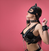 Brunette In Bdsm Leather Straps On A Pink Background In A Cat Mask In Handcuffs For Sex Games
