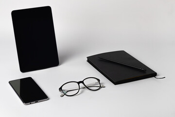 Close up of notebook, pencil, eyeglasses, electronic tablet and smartphone on light background, medical health concept, poor eyesight