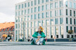 © Masson - Stylish teenage student girl with headphones sits on city street of Wroclaw, Poland