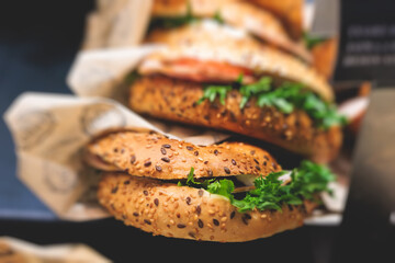 Beautifully decorated catering banquet table on event with different food snacks and appetizers setting with bagel and sandwiches, triange, baguette club submarine sandwich, on a wooden plate