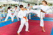 © JackF - Diligent positive schoolchilds boy and girl practicing karate kicks in pairs in gym
