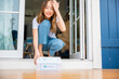 Close up hands of sick Asian woman sitting at door to receive medication first aid pharmacy box from hospital delivery service at floor home, merchandise medicine online business, healthcare concept