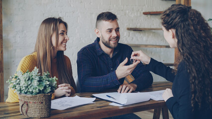 Wall Mural - Loving couple is purchasing house signing sales agreement with housing agent, getting key after making deal with realtor. Buying real estate concept.