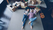 © silverkblack - Top view of adorable young couple lying on floor of their new apartment in bedroom talking. Carton boxes, guitar, carpet and bed are visible.