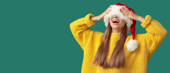 Poster - Happy young woman in Santa hat on green background with space for text