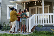 © Seventyfour - Full length portrait of happy black family embracing while standing on porch of new house, copy space
