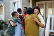 © Seventyfour - Big African American family embracing outdoors welcoming guests for party