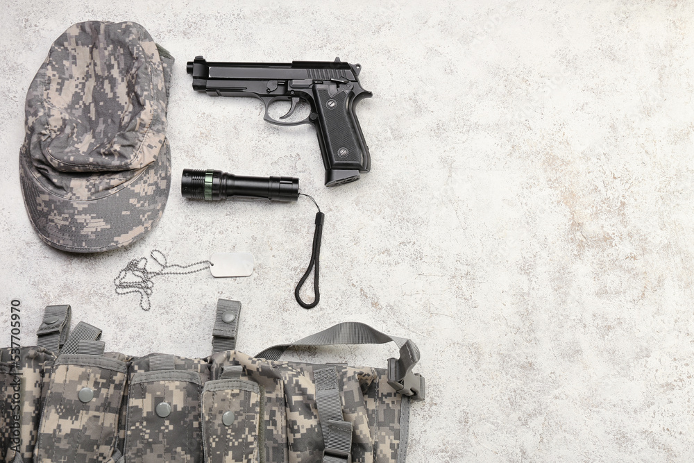 Military uniform, gun, flashlight and tag on light background