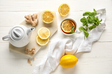 Cup of black tea with lemon, mint, ginger and teapot on white background