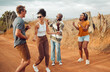 © K Abrahams/peopleimages.com - Friends, dance and nature with a man and woman group having fun outdoor during travel or adventure together. Summer, vacation and freedom with young people dancing on a sand road in the desert