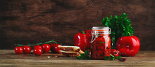 Baked Canned Red Paprika Pepper, Marinated  With Chili, Garlic And Herbs In Glass Jar. Rustic Wood Kitchen Table Background. Banner