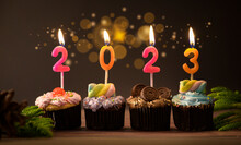 Colorful Cupcakes With Candles To Celebrating New Year's 2023 On Wooden Table , Holiday Background Concept