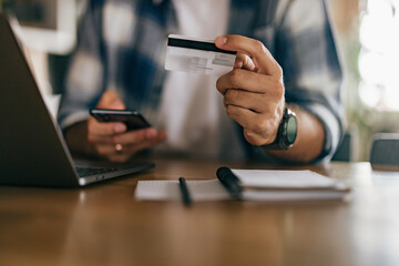 close up of a male person holding a credit card and a mobile pho