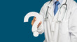 Midsection of a doctor in uniform holding a white question mark while standing on a blue background