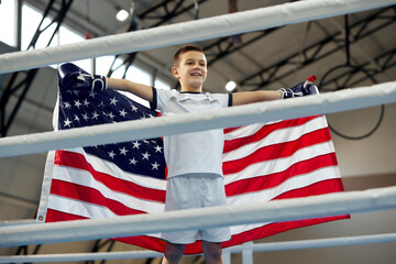 Winner emotions. Little boy, boxer with american flag on his shoulders celebrating his victory. Strength, sport, win, success, achievements.