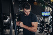 © Dusko - Good looking handsome male athlete exercising in modern fitness gym. Dark muddy light with strong shadows. Indoors sport concept.