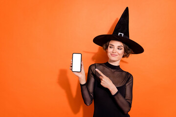 Wall Mural - Portrait of attractive enchant lady look indicate finger empty space phone display isolated on orange color background