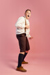 Fright, fear. Scared teen boy in white shirt and shorts with suspenders isolated over pink background. Stress, emotions, retro fashion, dieting