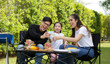 © atitaph - Asian family happy, bright, cute daughter, barbecues in the courtyard with blue sky and greenery in the backyard