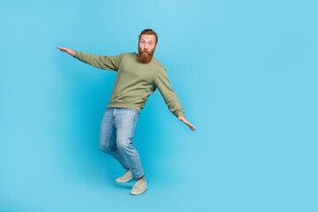 Full size photo of nice young guy try keep balance falling leaning surfing nervous wear khaki clothes isolated on cyan color background