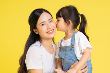 Wall Mural - image of asian mother and daughter posing on a yellow background