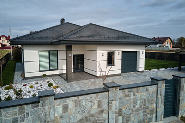 Wall Mural - New residential house cottage and attached garage with big paved fenced yard on sunny day in modern suburban area. Real estate property concept