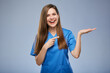 © Yuriy Shevtsov - Smiling doctor woman in blue medical suit holding empty hand with copy space for product and pointing wiht finger.. Isolated female portrait.