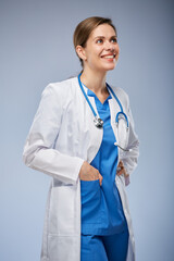 Wall Mural - Smiling doctor woman in white coat and midical suit looking away. Isolated portrait.