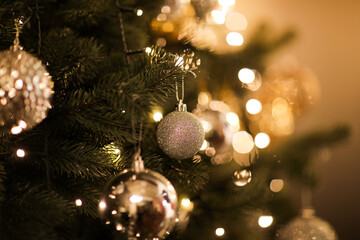 close up view of beautiful fir branches with shiny golden bauble or ball, xmas ornaments and lights,