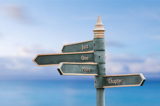 just one more chapter four word quote written on fancy steel signpost outdoors by the sea. Soft Blue ocean bokeh background.